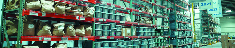 A storage area in a factory filled with white bags of products wrapped in plastic. 